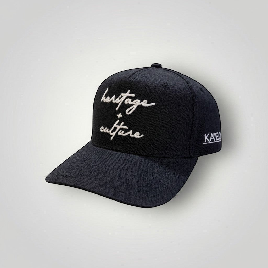 KA'EO Apparel black cotton baseball cap with embroidered 'heritage + culture' script and side branding.
