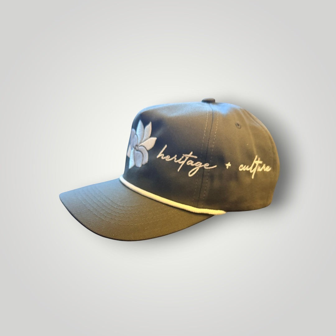 KA'EO Apparel olive green baseball cap with white embroidered Sampaguita flower and "heritage + culture" text.