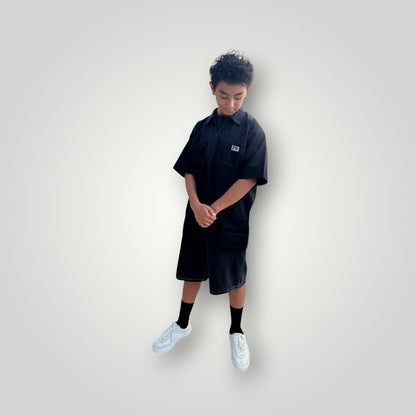 KA'EO x Ben Davis black poly-cotton twill work shirt with quarter-zip and chest pockets. Model is wearing shorts and sneakers.