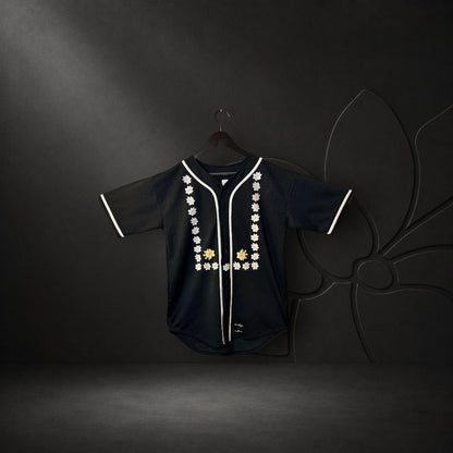 KA'EO Apparel black mesh baseball jersey featuring white piping and intricate Sampaguita floral embroidery on the front.