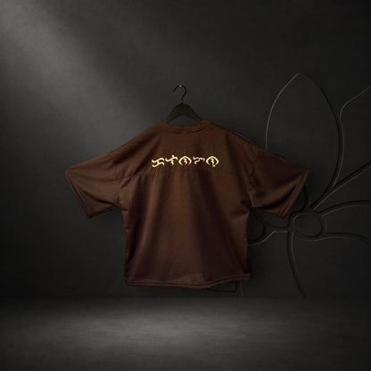 KA'EO Apparel brown mesh cropped football jersey with gold Baybayin script on the back, hanging against a dark background.