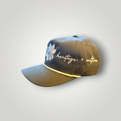 KA'EO Apparel olive green baseball cap with white embroidered Sampaguita flower and "heritage + culture" text.
